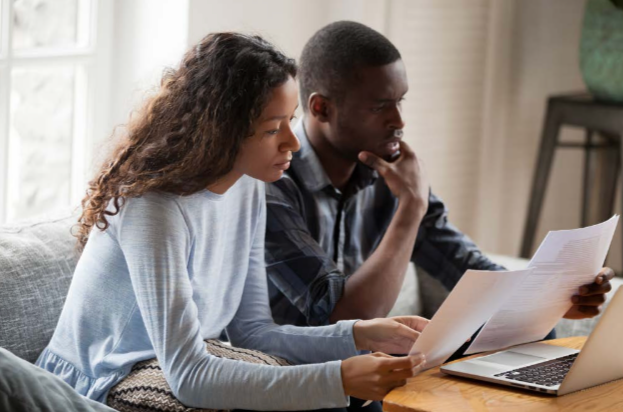 Two people, a man and a woman, looking at paperwork and a computer